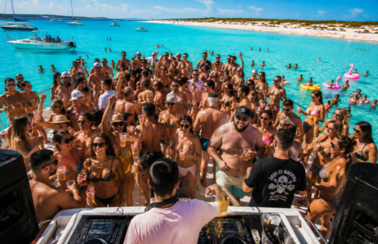 Guests enjoying an Ibiza boat party with reggaeton and techno DJs on separate decks