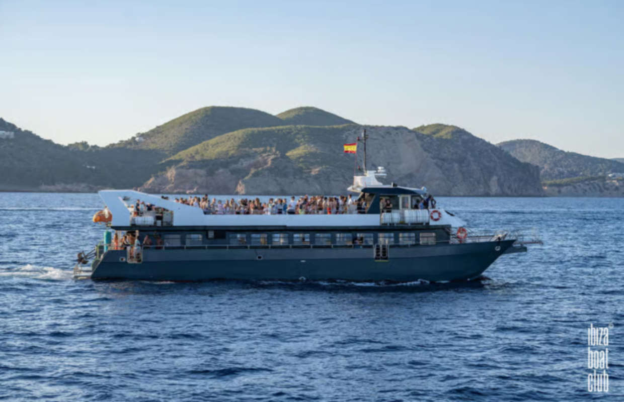 Ibiza boat party cruise sailing along the coastline with guests enjoying the Mediterranean Sea
